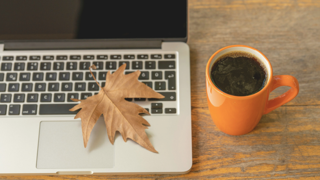 feuille d’automne tombée sur un ordinateur portable à côté d’un café chaud