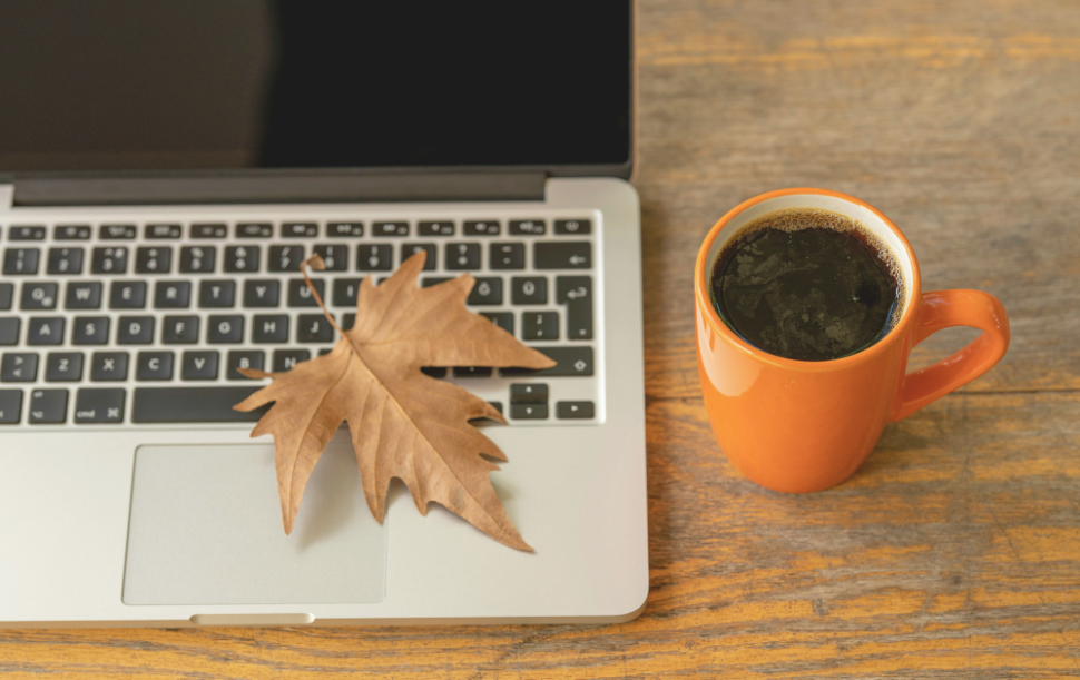 feuille d’automne tombée sur un ordinateur portable à côté d’un café chaud