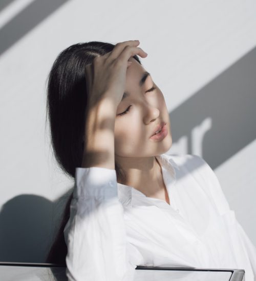 Femme entrepreneure sensible la main sur la visage, symbolisant une lassitude liée à son manque de confiance en soi