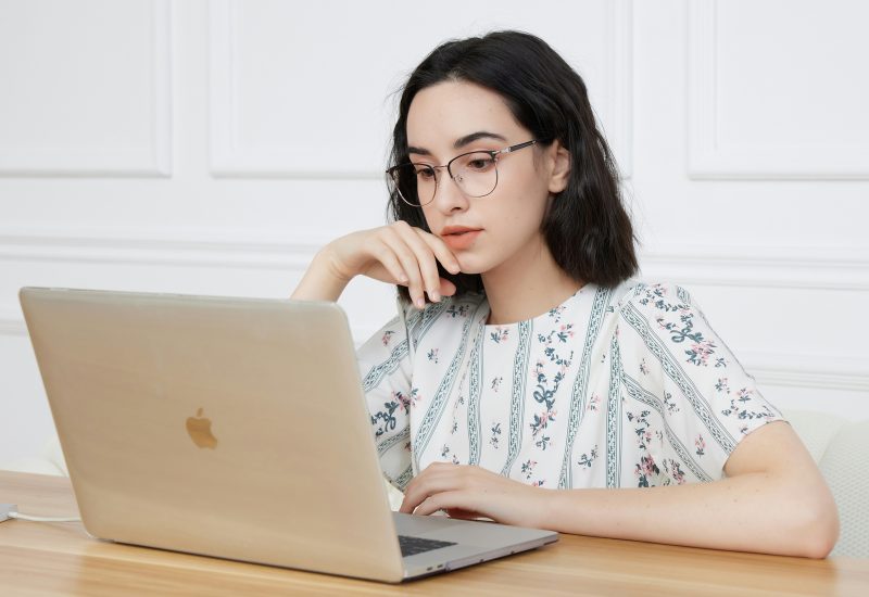 Entrepreneure sensible devant son PC, qui essaie de suivre un modèle d'organisation classique d'entrepreneur