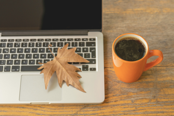 feuille d’automne tombée sur un ordinateur portable à côté d’un café chaud